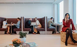 A woman taking a business call in the coworking lounge at 10 Avenue Kléber, surrounded by professionals.